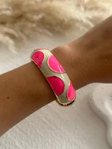 Close-up detail of a vibrant rose pink and cream enamel dopamine style bangle on wrist