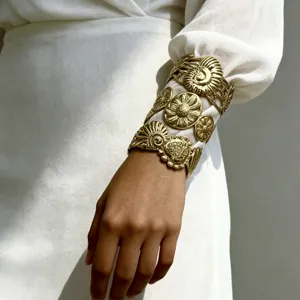 Vista ravvicinata di un ampio bracciale a polsino dorato con motivi floreali a rilievo
