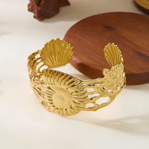 Primo piano dettagliato di un bracciale a polsino in acciaio dorato con foglie irregolari