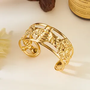 Dettaglio di un bracciale rigido in acciaio dorato con motivi di foglie irregolari