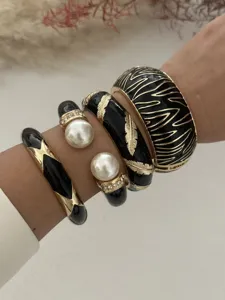 Nahaufnahme von kühnen schwarzen und goldenen Emaille-Armreifen mit Zebramuster