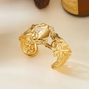 Dettaglio del bracciale rigido in acciaio dorato con motivo a granchio e foglie