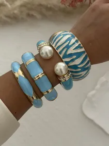 Detailansicht eines blauen Emaille-Armreifensets mit Zebramuster und Perlen am Handgelenk