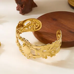 Dettaglio di un bracciale a fascia dorato con motivi di foglie irregolari e granchio