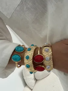 Detailed view of stacked gold bangles featuring turquoise and marble stones on a wrist