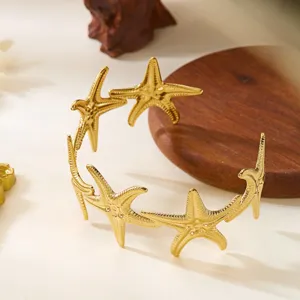 Dettaglio ravvicinato di un bracciale a polsino a forma di stella marina in acciaio oro.