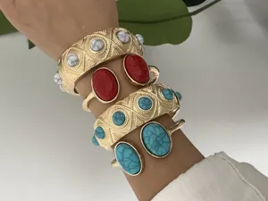 Bohemian style gold cuff bracelets set with turquoise and coral stones close-up