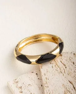 Detailaufnahme des schwarz-goldenen geometrischen Musters am klobigen Armreif.
