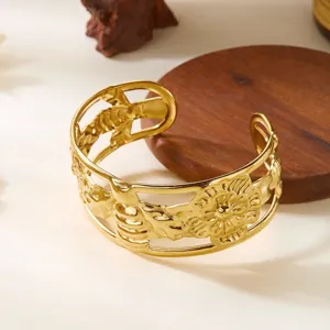 Dettaglio di un bracciale rigido largo in acciaio inossidabile dorato con motivi a foglia