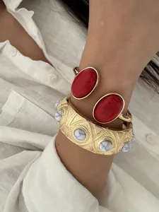 Detailed macro shot of stylish gold-tone layered bangles with red and white stones