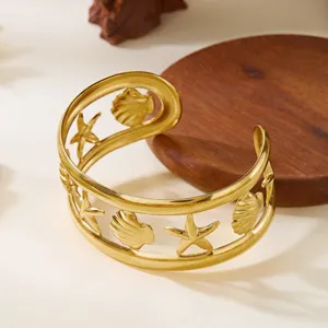 Dettaglio di un bracciale a fascia dorato con intagli di stelle marine e conchiglie