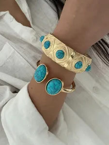 Detail view showing bohemian gold-tone bangles with turquoise stones on a woman's wrist.