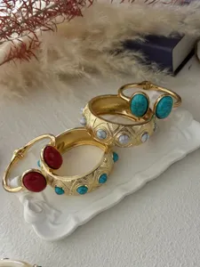 Detailed view of gold-tone bangles featuring turquoise and marble-patterned stones