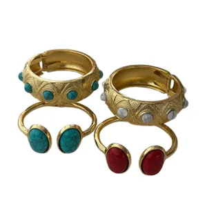 Bohemian gold alloy bangles set with turquoise and red stones on white background.
