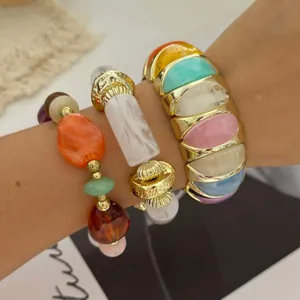 Close-up van macaron gekleurde stenen kralen armband set en goud brede manchet.