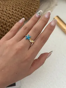 Detailansicht eines Meeresstern- und Muschelrings in Goldoptik getragen an der Hand