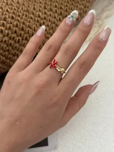 Detailansicht eines vergoldeten Rings mit Seestern und Muschel, rotem Emaille und Kristallen.