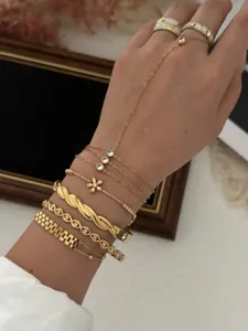 Detailed view of layered gold-tone zircon flower bracelets and a twisted metal bangle.