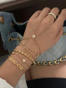 Detailed close-up of layered gold flower charm bracelets with a sparkling zircon ring