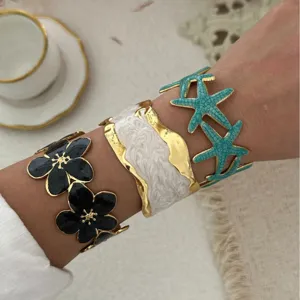 Set eleganter vergoldeter Emaille-Armspangen mit Blumen- und Seestern-Designs am Handgelenk