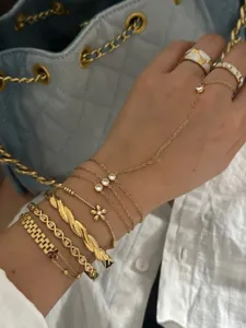 Detailed view of stylish stacked gold flower bracelets and zircon hand chain jewelry.