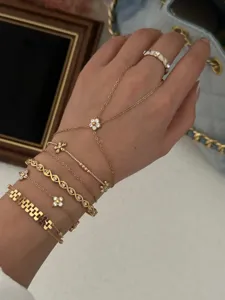Detailed view of layered gold-tone bracelets with zircon flower charms on hand