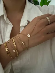 Detailed close-up showing stacked gold chain bracelets and hand chain with delicate flower charms