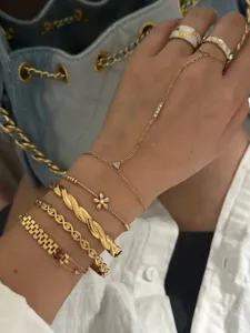 Detailed shot of stacked gold-toned bracelets and flower zircon hand chain on wrist