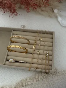 Detailed view of gold chain bracelets and bangles displayed in a beige jewelry tray