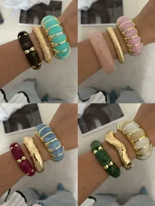 Detailansicht farbenfroher elastischer Armbänder mit Goldakzenten und Harztexturen.