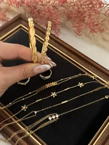 Close-up of gold flower zircon chain bracelets and bangles on a black velvet tray