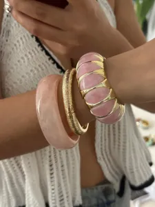 Nahaufnahme von rosa Bonbon-Armbändern und goldgeriffeltem Armreif im Set