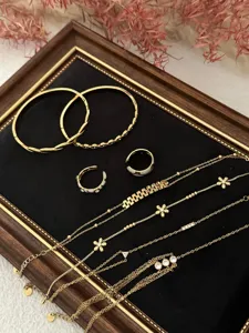 Detailed view of gold plated jewelry set with delicate zircon flowers and white enamel