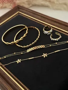 Detail view of gold floral zircon bracelets and rings set on black velvet display