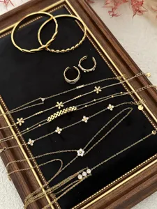 Detailed view of gold-tone flower zirconia bracelets and necklaces on black velvet