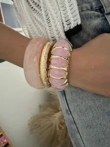 Detailaufnahme eines rosa bonbonfarbenen elastischen Armbands mit goldenem Reif