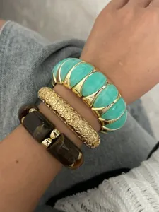 Detail von gestapelten Mode-Armbändern: blaugrünes elastisches Band, goldener Armreif.