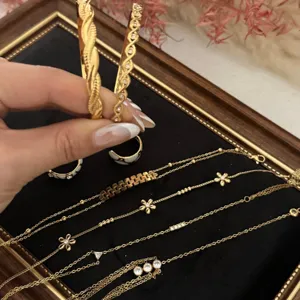 Set of gold plated flower zircon bracelets and bangles for stacking on velvet tray.