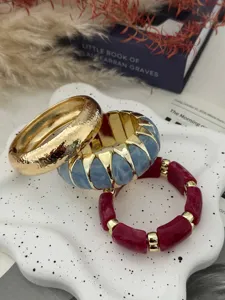 Stapel bunte Harz-Stretch-Armbänder und ein gehämmerter Goldreif zur Dekoration.