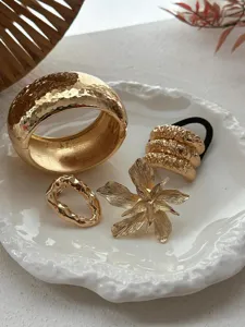 Detailopname van een elegante gehamerde gouden sieradenset met armband en bloem
