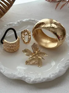 Detailweergave van een gouden vintage sieradenset met armband en een bloemenspeld