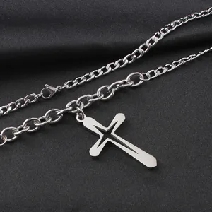 Détail en gros plan d'un collier à maille gourmette en acciaio con pendentif croix