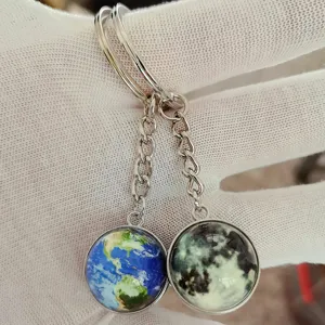 Close-up detail of double-sided glass ball universe planet keychain with earth and moon pendants.
