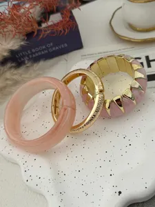 Detailansicht von bonbonfarbenen Armbändern mit Marmorharz- und goldfarbenen Metalltexturen.