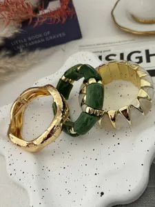 Nahaufnahme von bunten elastischen Armbändern und einer goldenen Metallmanschette