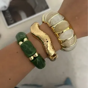 Trendiges Set aus breiten bonbonfarbenen elastischen Armbändern und goldenem Armreif