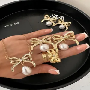 Detail des goldenen Schmucksets mit Schleife und Perle, inkl. Kette, Ohrringen und Ring.