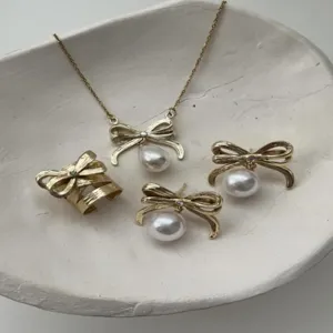Detailansicht des goldenen Schleifen-Schmucksets mit eleganten Perlen und Bandstruktur