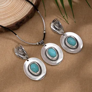 Vintage ethnic jewelry set with turquoise hat pendants on burlap background