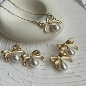 Detailansicht der goldenen Schleifenhalskette und der eleganten Perlenohrringe